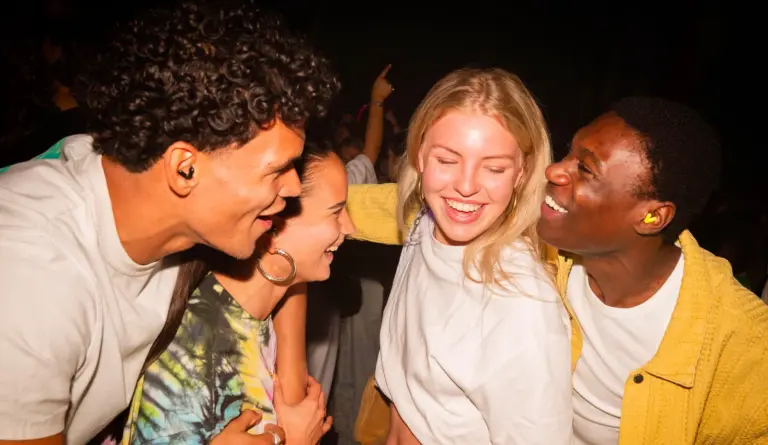 Vier mensen op een feestje die gehoorbescherming dragen
